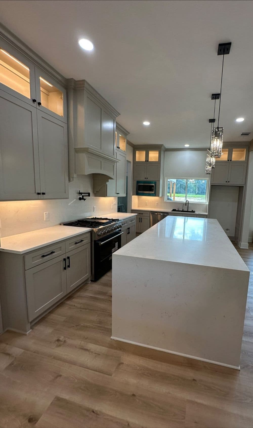 Modern kitchen with gray cabinets, white countertops, and stainless steel appliances.
