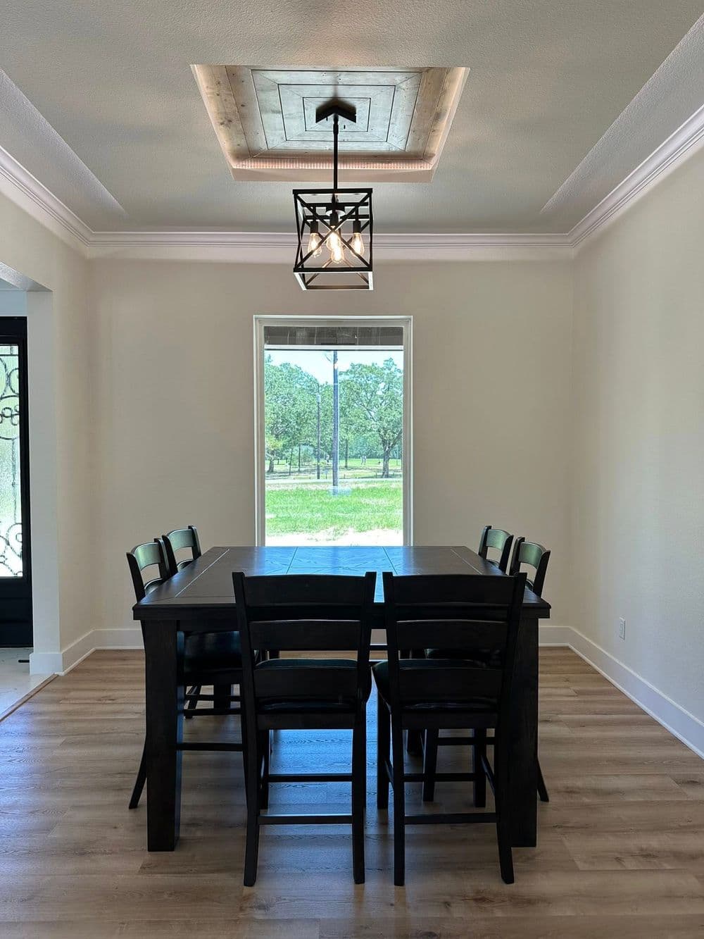 Modern dining area with a wooden table, black chairs, and a stylish light fixture.