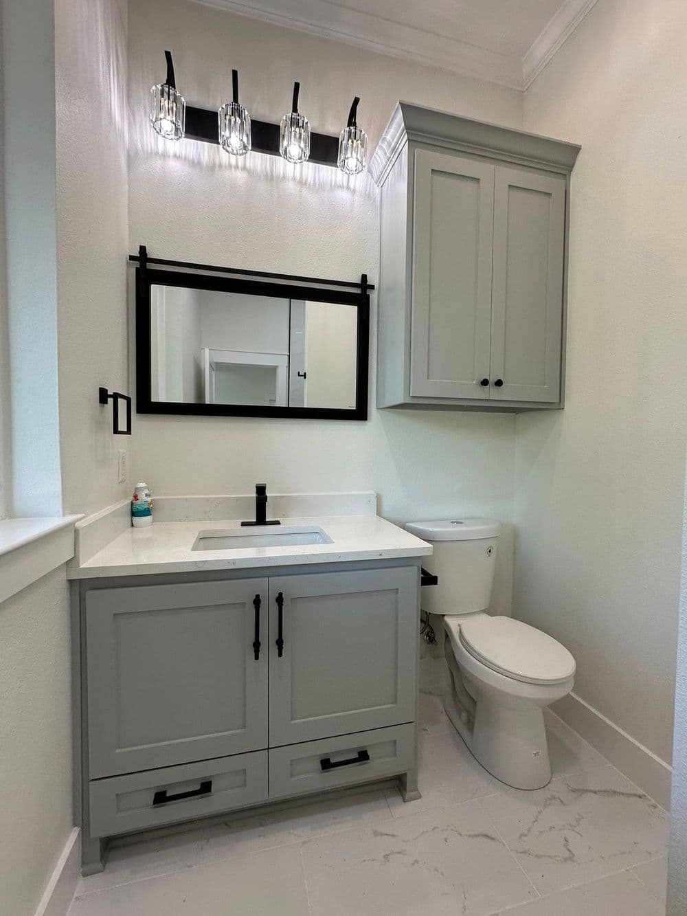 Modern bathroom with gray cabinetry, sleek mirror, and stylish lighting fixtures.