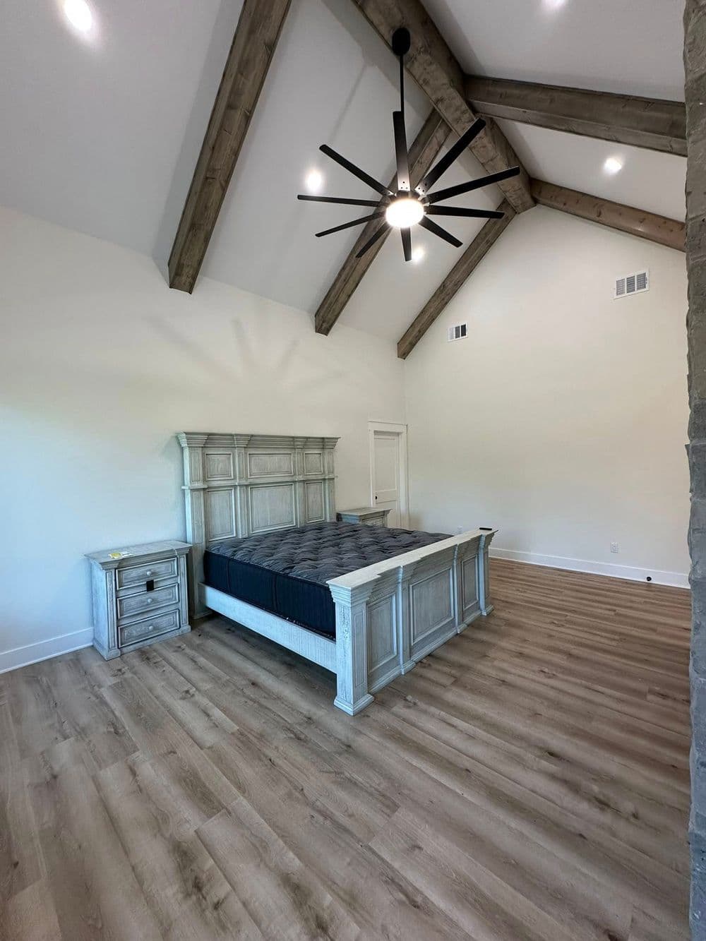 Spacious modern bedroom with vaulted wooden ceiling and large bed. Stylish decor and natural light.