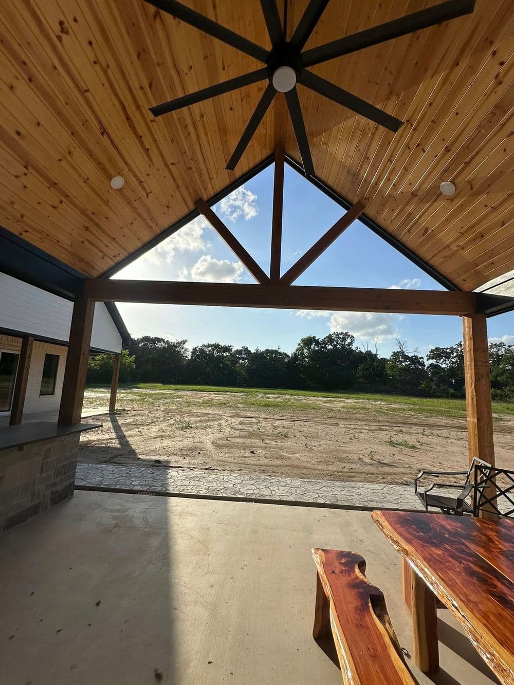 Open outdoor patio with a wooden ceiling, large fan, and scenic view of the landscape.